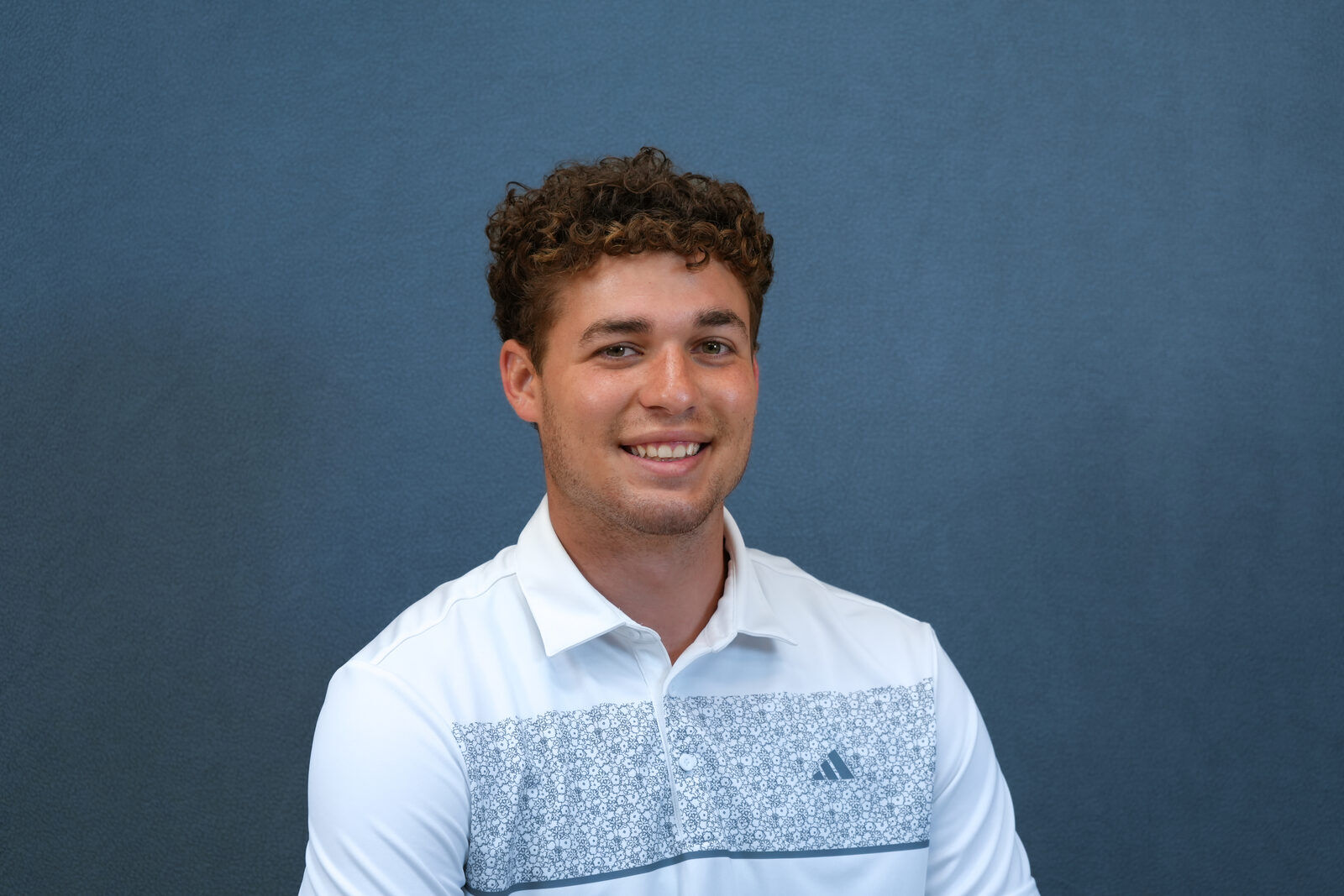 Studio headshot, male subject, white polo
