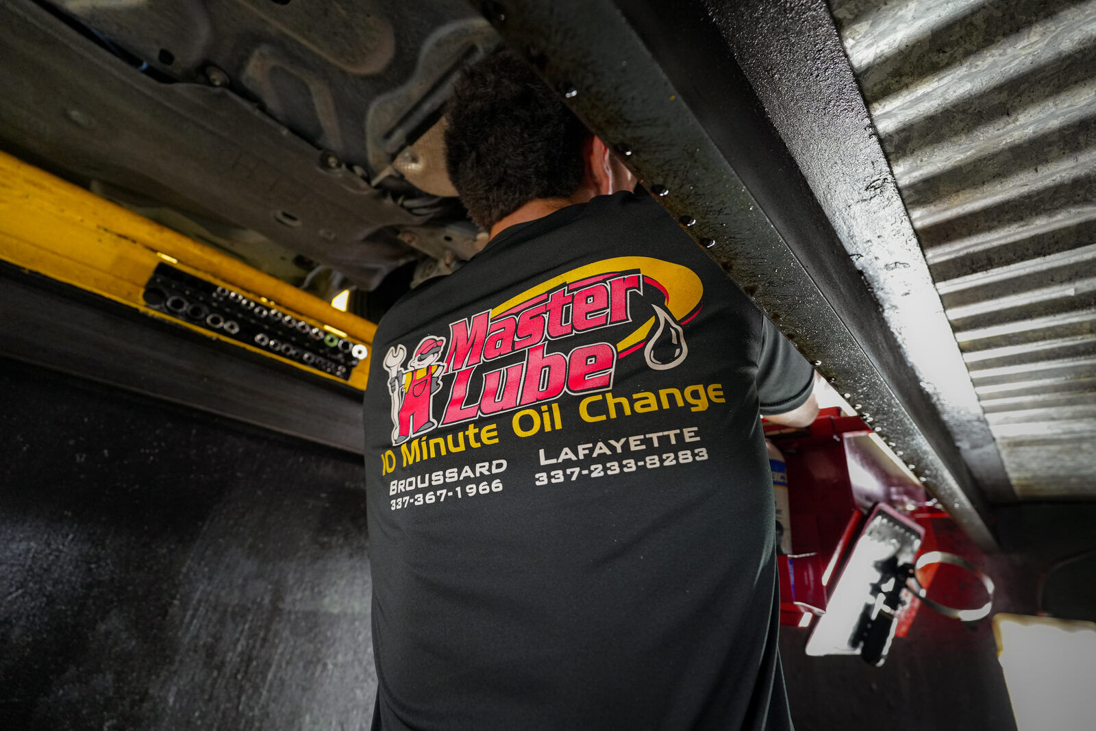 Master Lube technician at work, low angle beneath a vehicle